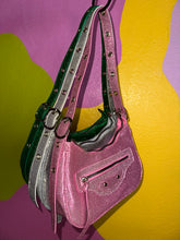 Load image into Gallery viewer, Pink glittery handbag with a green strap on a multicolored background
